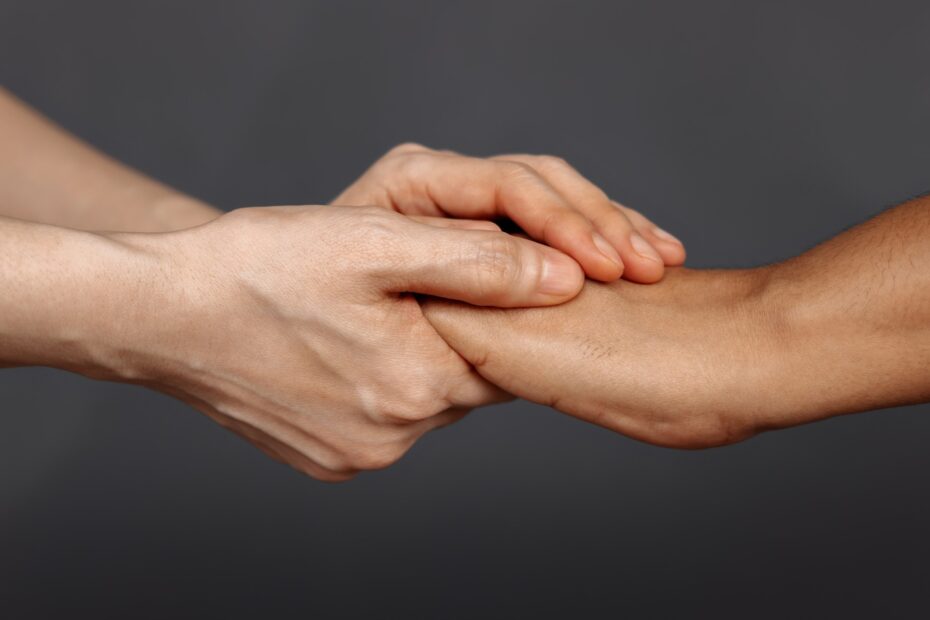 dwie dłonie męskie trzymają jedną dłoń
